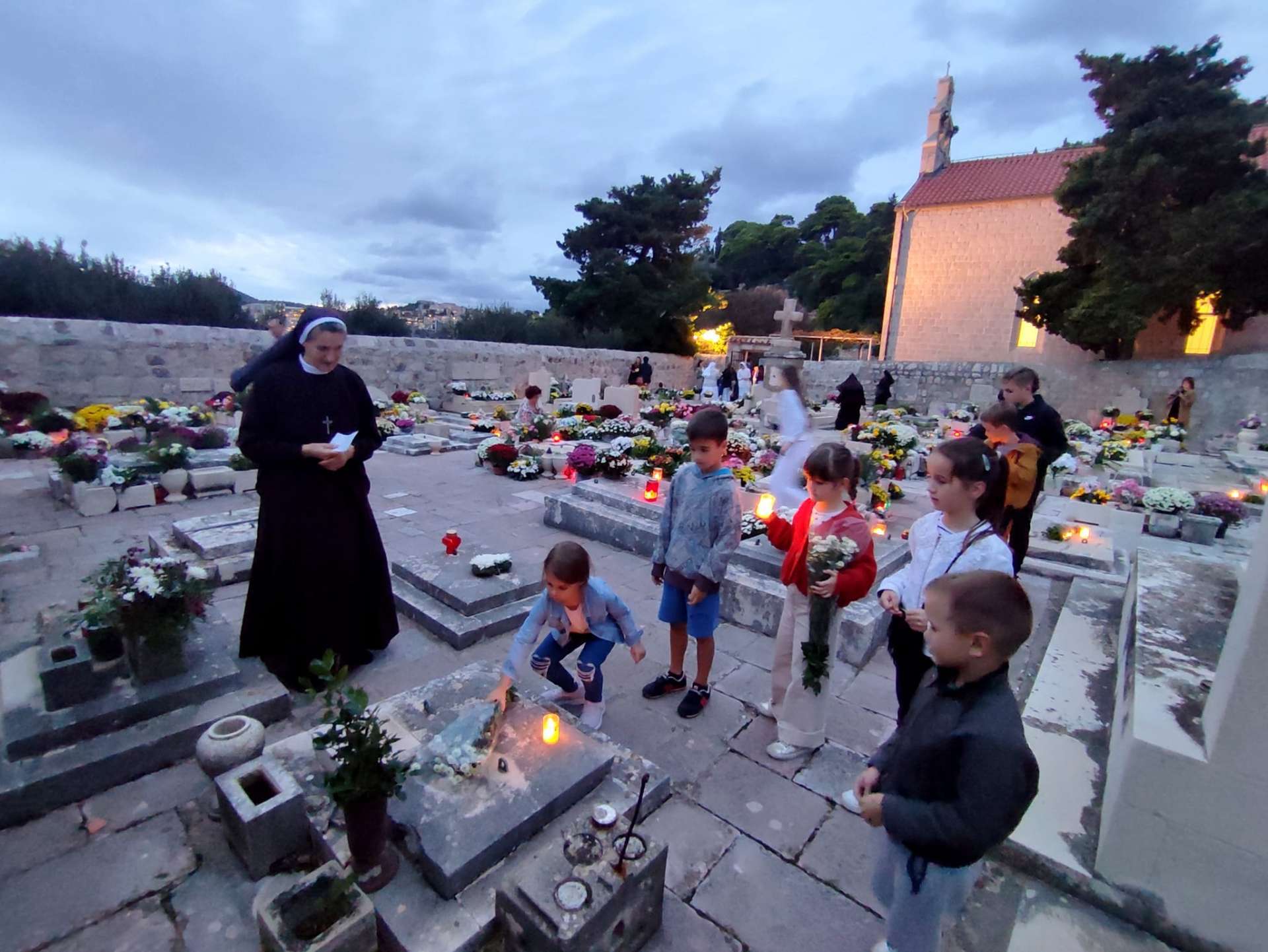 Akcija “Sjetimo se” na Dančama: Djeca i redovnice okitili grobove i pomolili se za pokojne